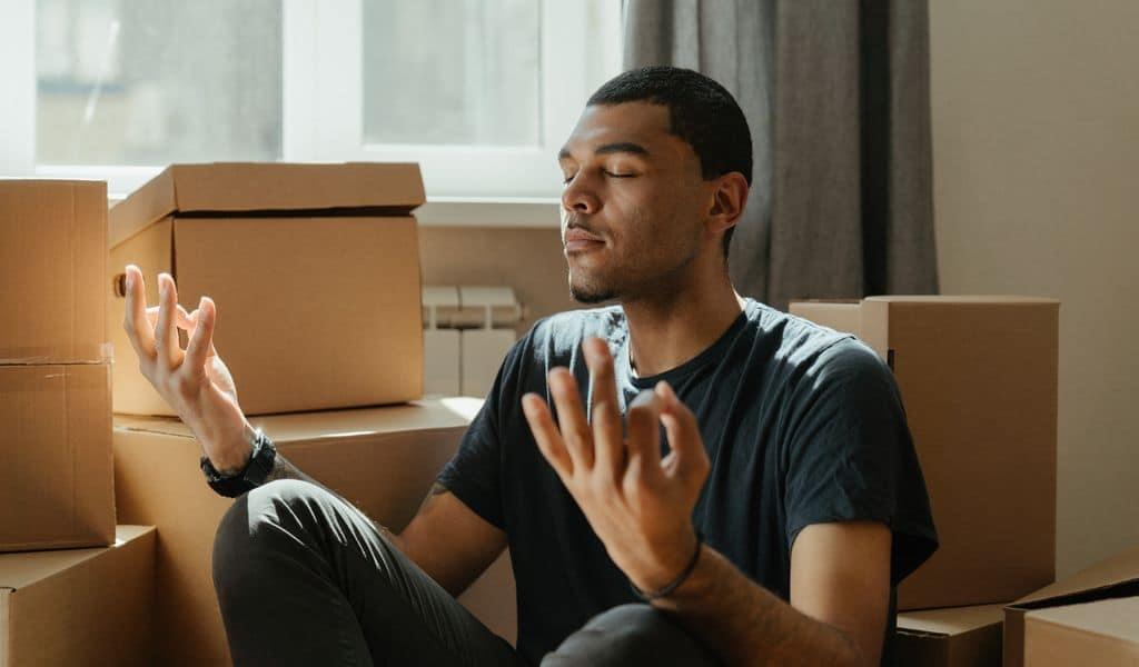 Man meditating amongst moving boxes