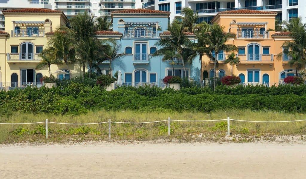 Three pastel houses sit side-by-side on the Florida beachfront