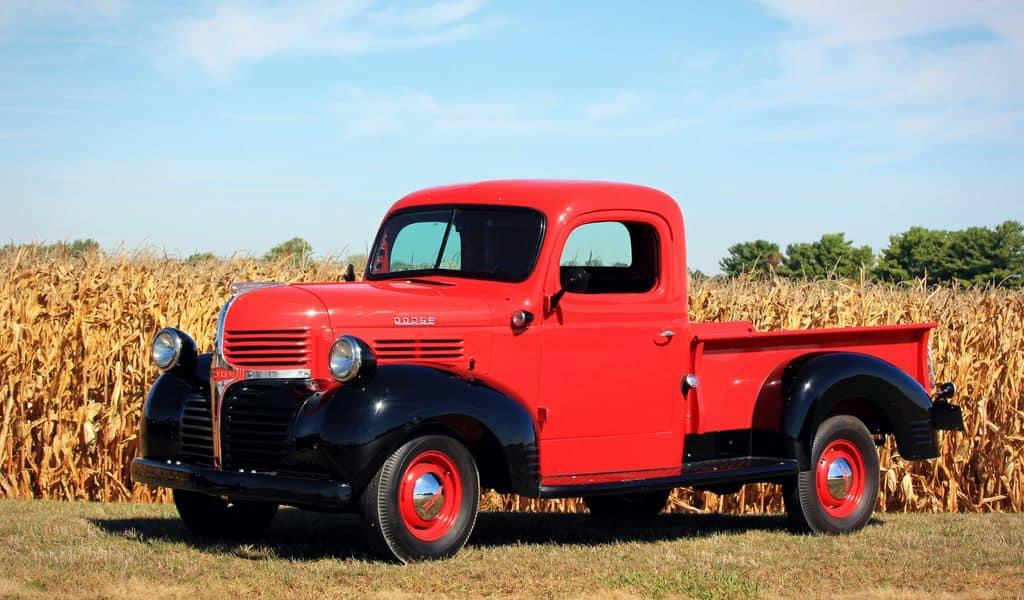 A red truck stands before a corn field