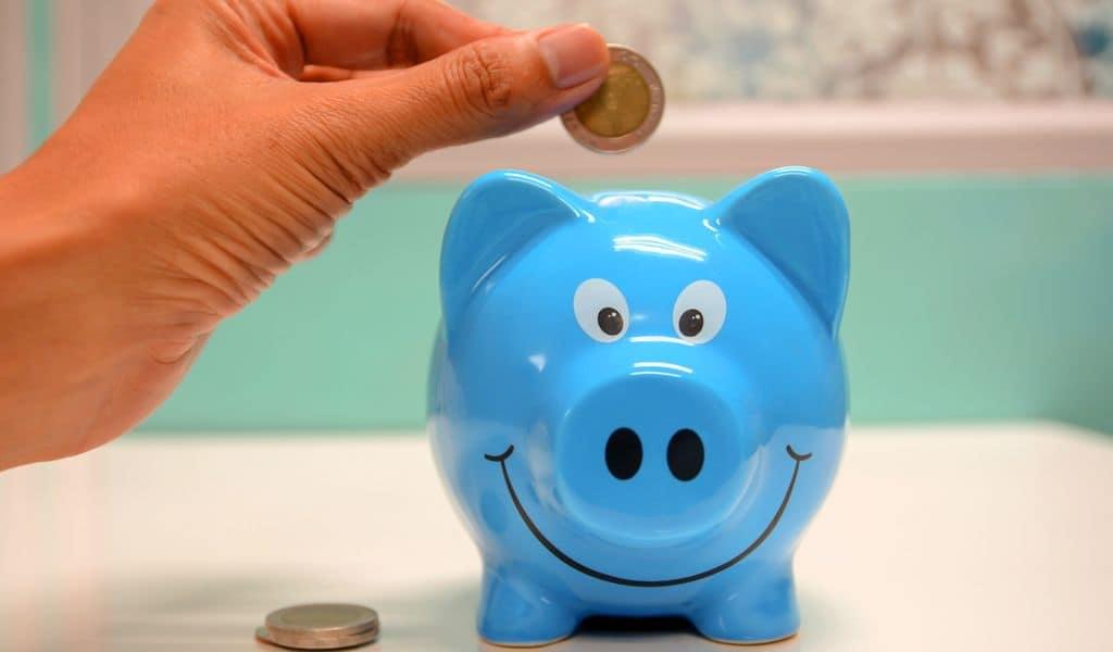 Hand dropping a coin in a piggy bank