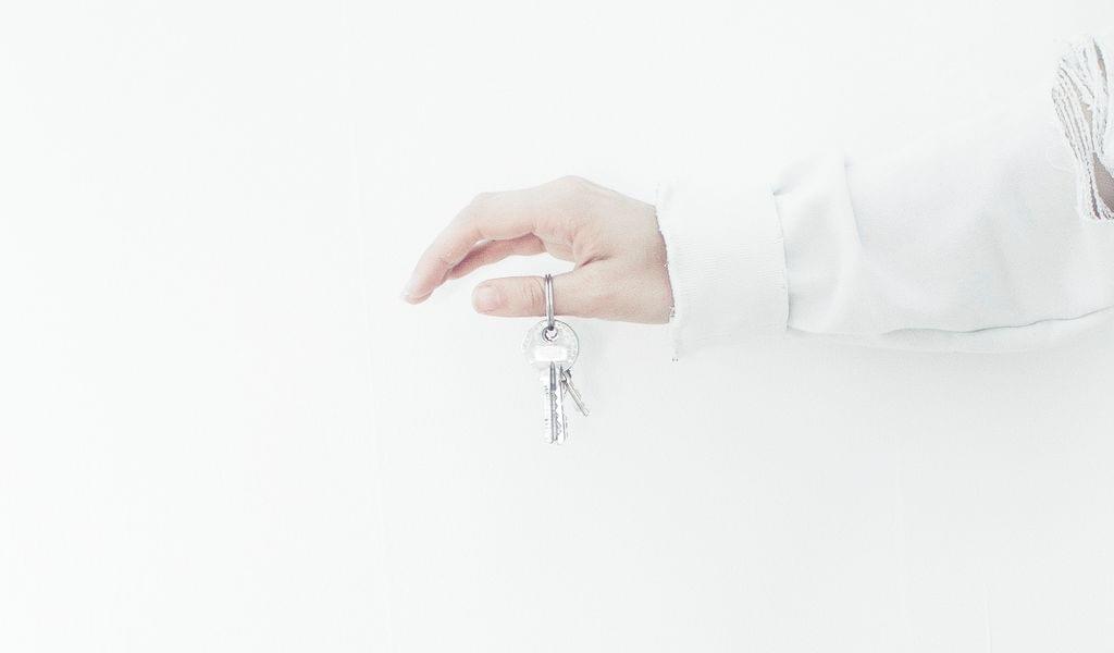 A hand brandishing residential keys against a white background