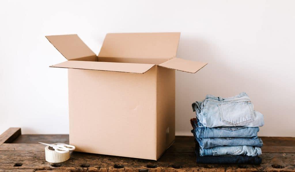 Stack of jeans near a carton box and tape