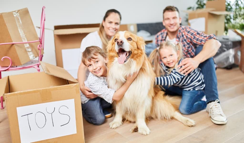 A happy family and their pet dog with unpacked moving boxes