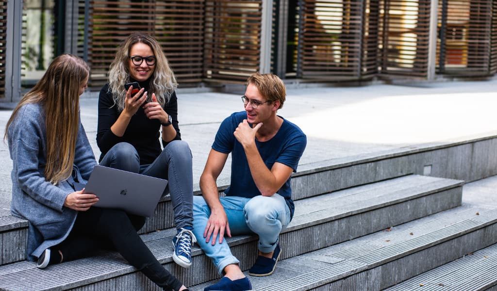 Three students talking to each other on the stairs