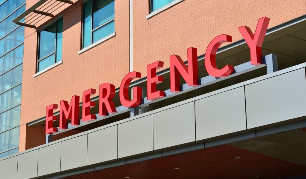 Red emergency sign against a red brick hospital building