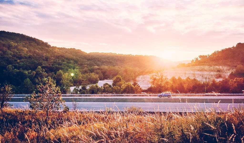 Vehicle travelling on a road during sunset surrounded by beautiful scenery