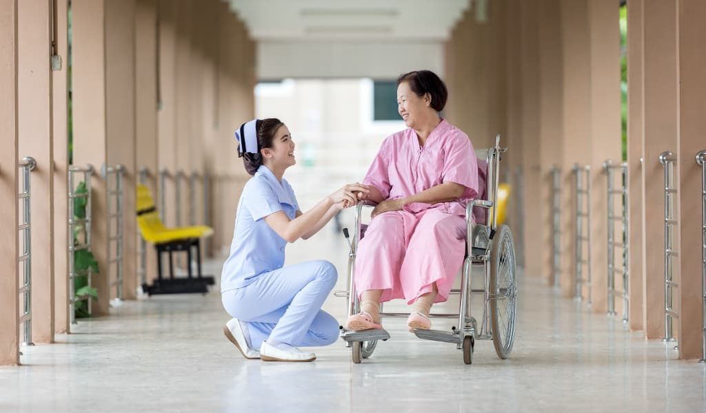 Woman in pink sitting in wheelchair with doctor kneeling beside her