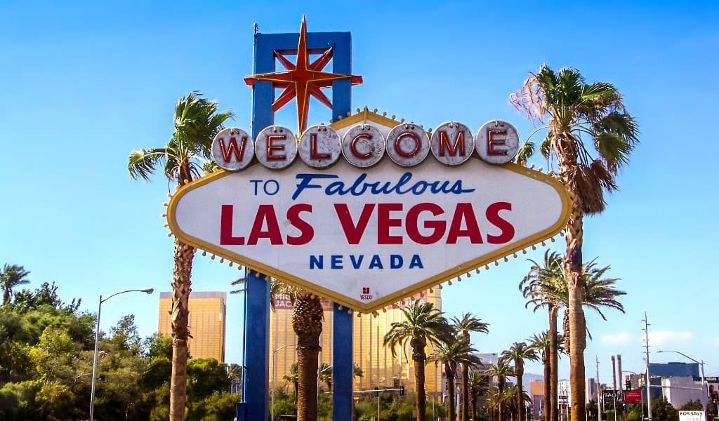 Large “Welcome to Las Vegas” signboard with palm trees and buildings in the background