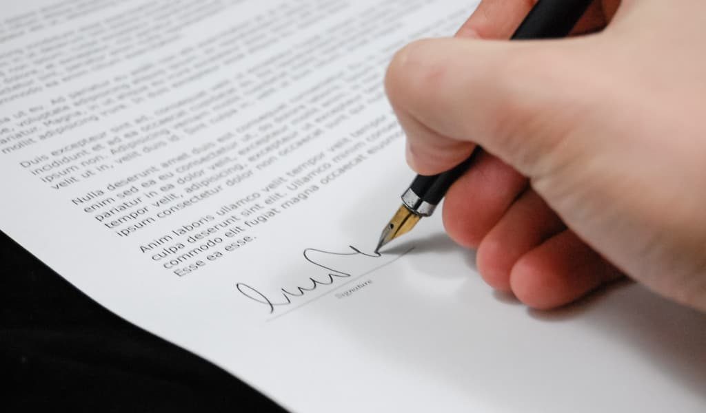 Person signing a formal document with a fountain pen