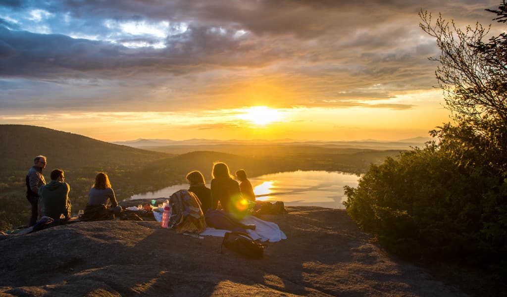 A group of people having a picnic under a sunset