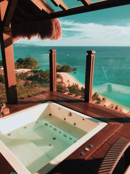 Inset hot tub in a wooden porch above a teal sea